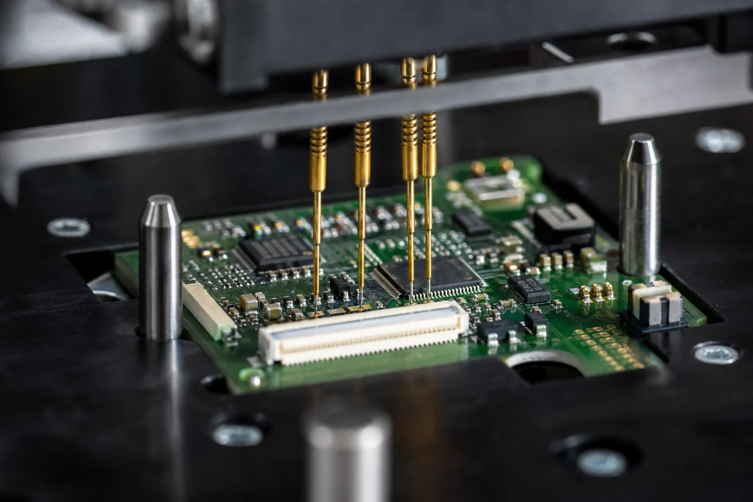 Close-up of spring probes contacting a populated circuit board inside a PCBA functional test fixture.